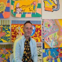 Walter in front of his artwork depicting colorful science characters