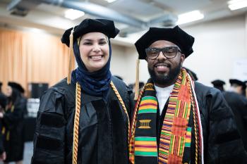 two graduates in full regalia.
