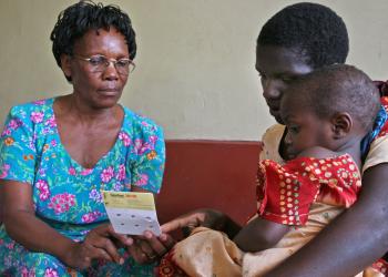 seated child, parent, and nurse examine a small sheet of paper