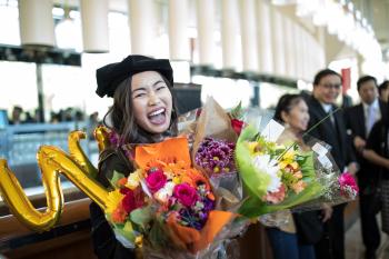 graduate with balloons and flowers