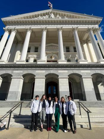 group stands in front of a government building.
