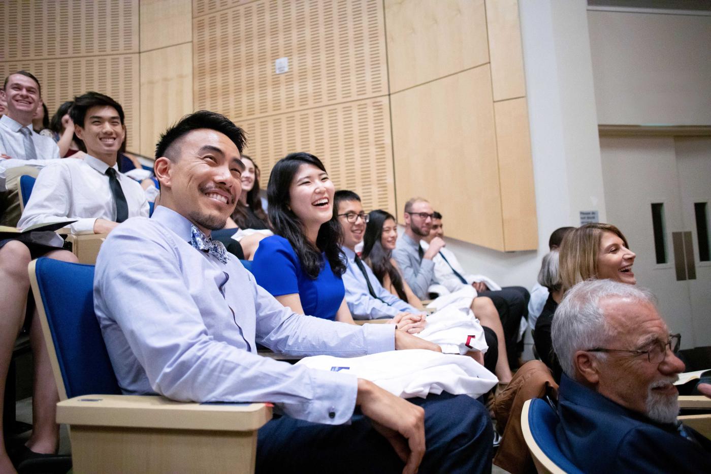 Laughing students sit in the auditorium.